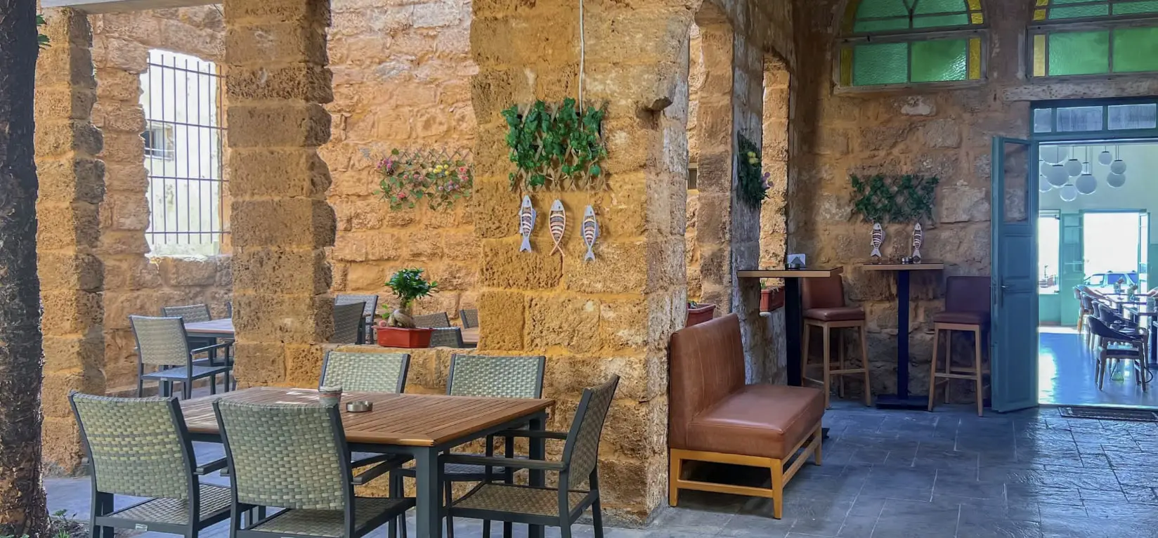 The dining room at The Sailor Woman - vaulted sandstone walls, wooden tables and painted wooden fish hung between the arches